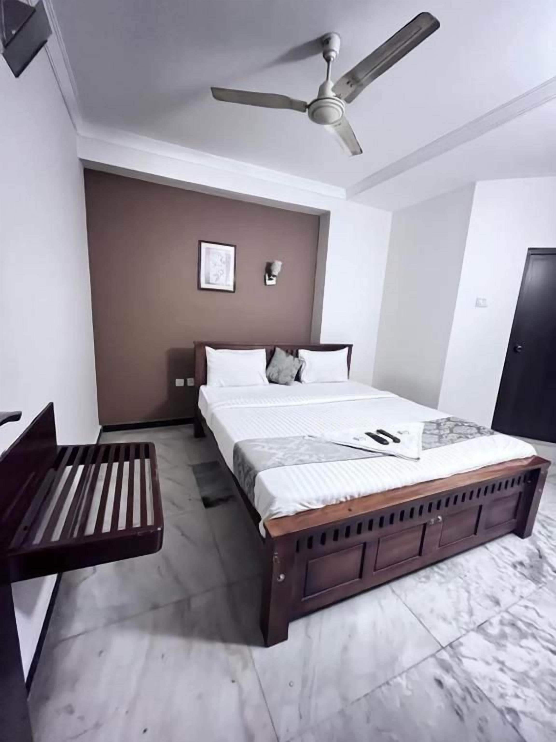 Un dormitorio con cama, escritorio, ventilador de techo y una puerta.