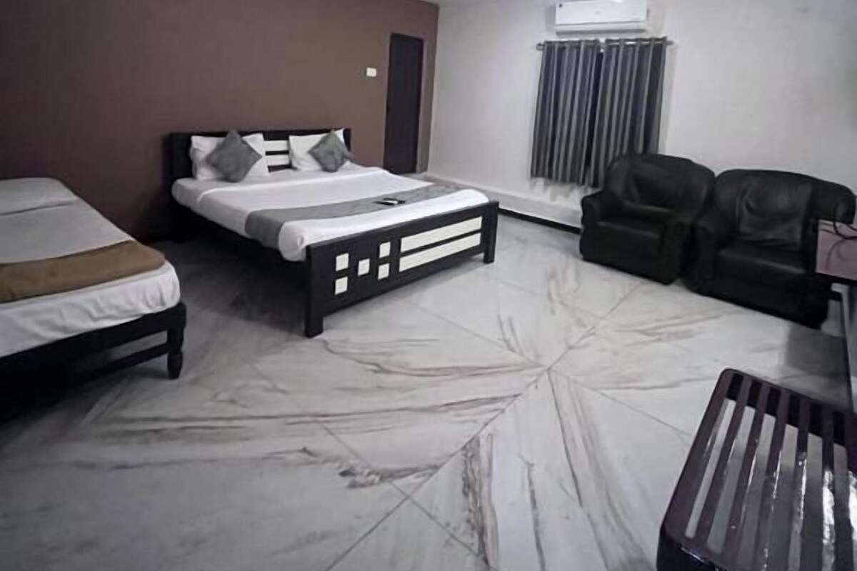 Quarto de hotel com cama, sofá, mesa de centro e ventoinha no teto.