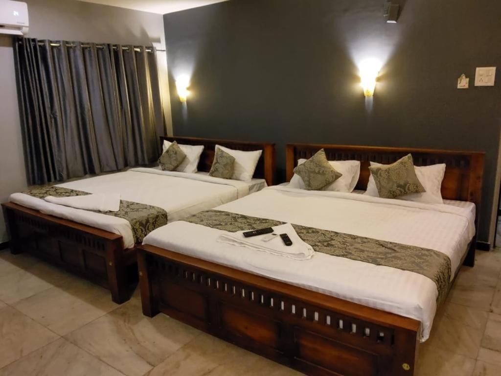 A hotel room with two beds, a dark wall, and a curtain.
