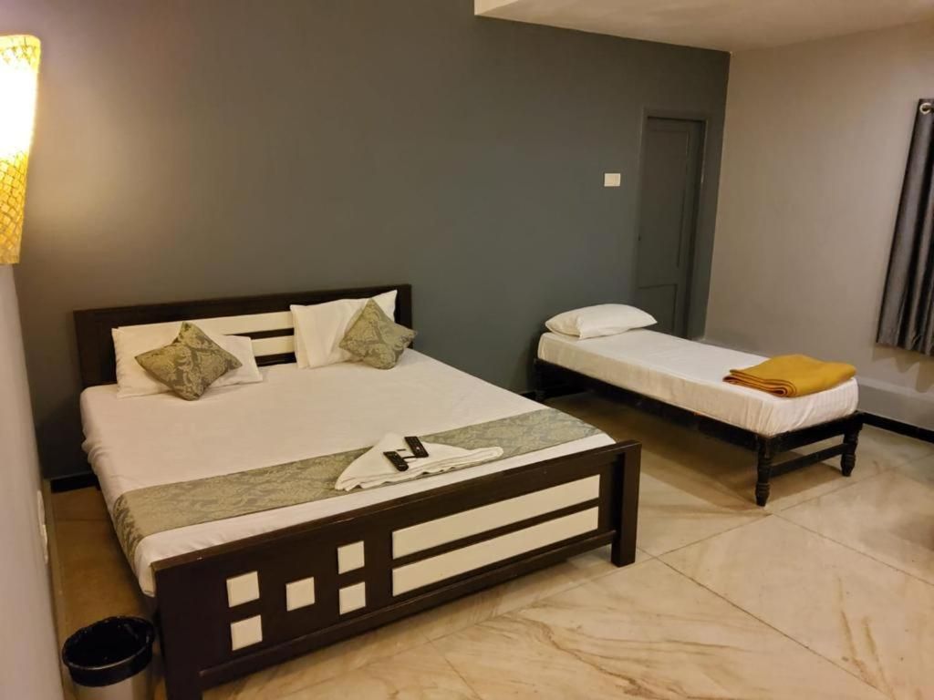 Un dormitorio con una cama grande y una más pequeña, ambas con cabeceros de madera y ropa de cama blanca.