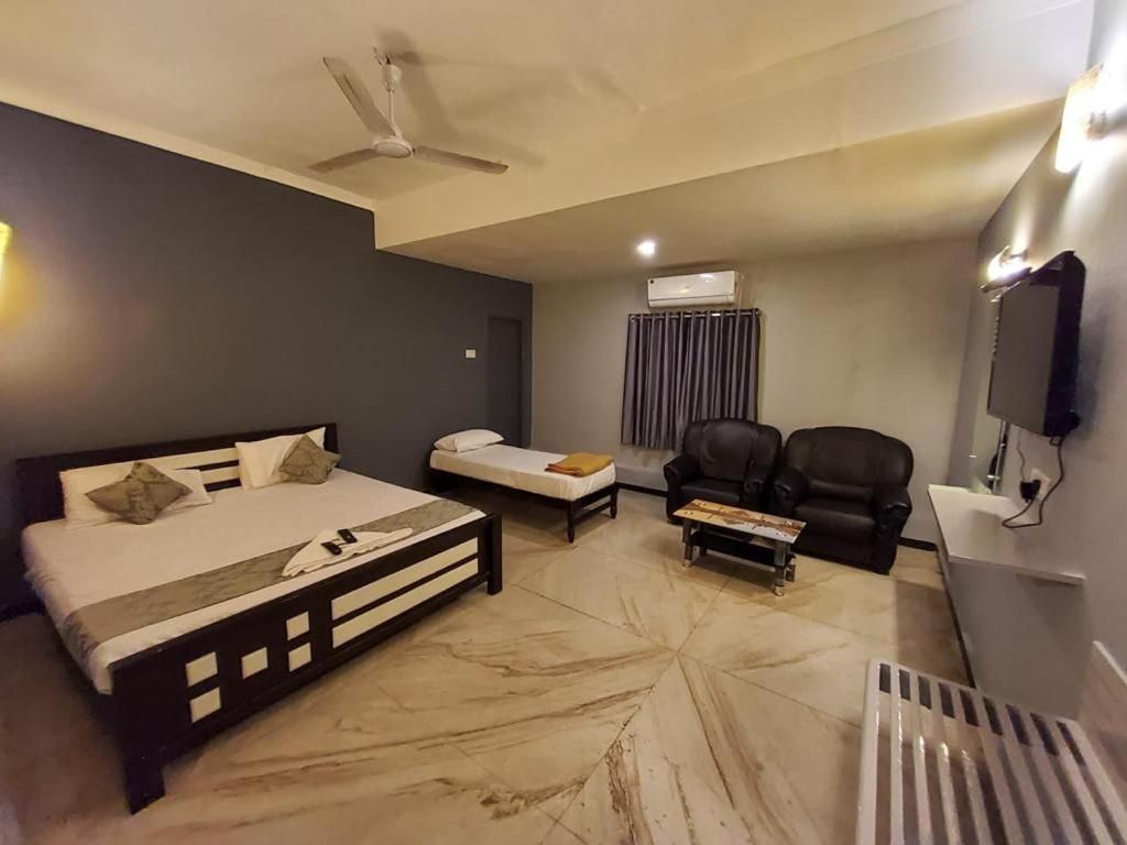 Una habitación de hotel con cama, sofá, mesa de centro, televisor y aire acondicionado.
