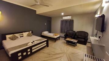 Una habitación de hotel con cama, sofá, mesa de centro, televisor y aire acondicionado.