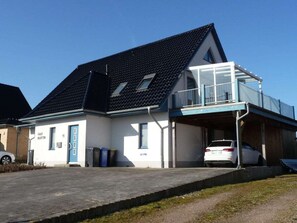 A two-story building with a garage, a covered parking area, and a small balcony. - Maritime House Semi-detached House Wismar (Klütz)