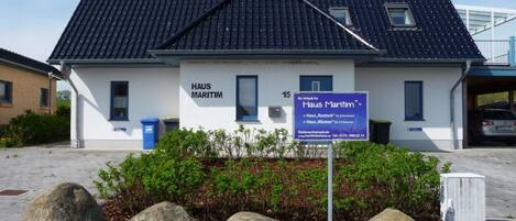 Un edificio con la leyenda 'HAUS MARITIM', un cartel que indica '15' y servicios para 'Haus Rostock' y 'Haus Wismar'.
