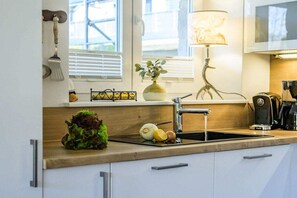 A kitchen with a sink, a plant, a lamp, and a window with blinds. - Holiday apartment with 2 bedrooms (Garmisch-Partenkirchen)