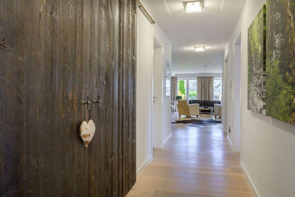 A hallway with a wooden door, a heart-shaped decoration, and a living area with a sofa and a coffee table.
