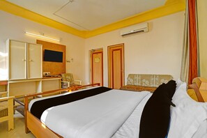 A hotel room with a bed, a desk, a chair, and a wardrobe. - Classic Hotel Vrundavan Residency (Vadodara)