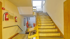 Una escalera con barandilla de madera y un extintor de incendios montado en la pared.