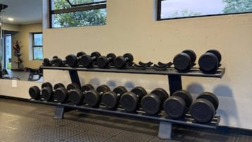 Une salle de sport équipée d’un porte-haltères, dotée d’un sol à motifs et de fenêtres donnant sur des arbres.