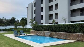 Um edifício moderno com piscina e espreguiçadeiras.