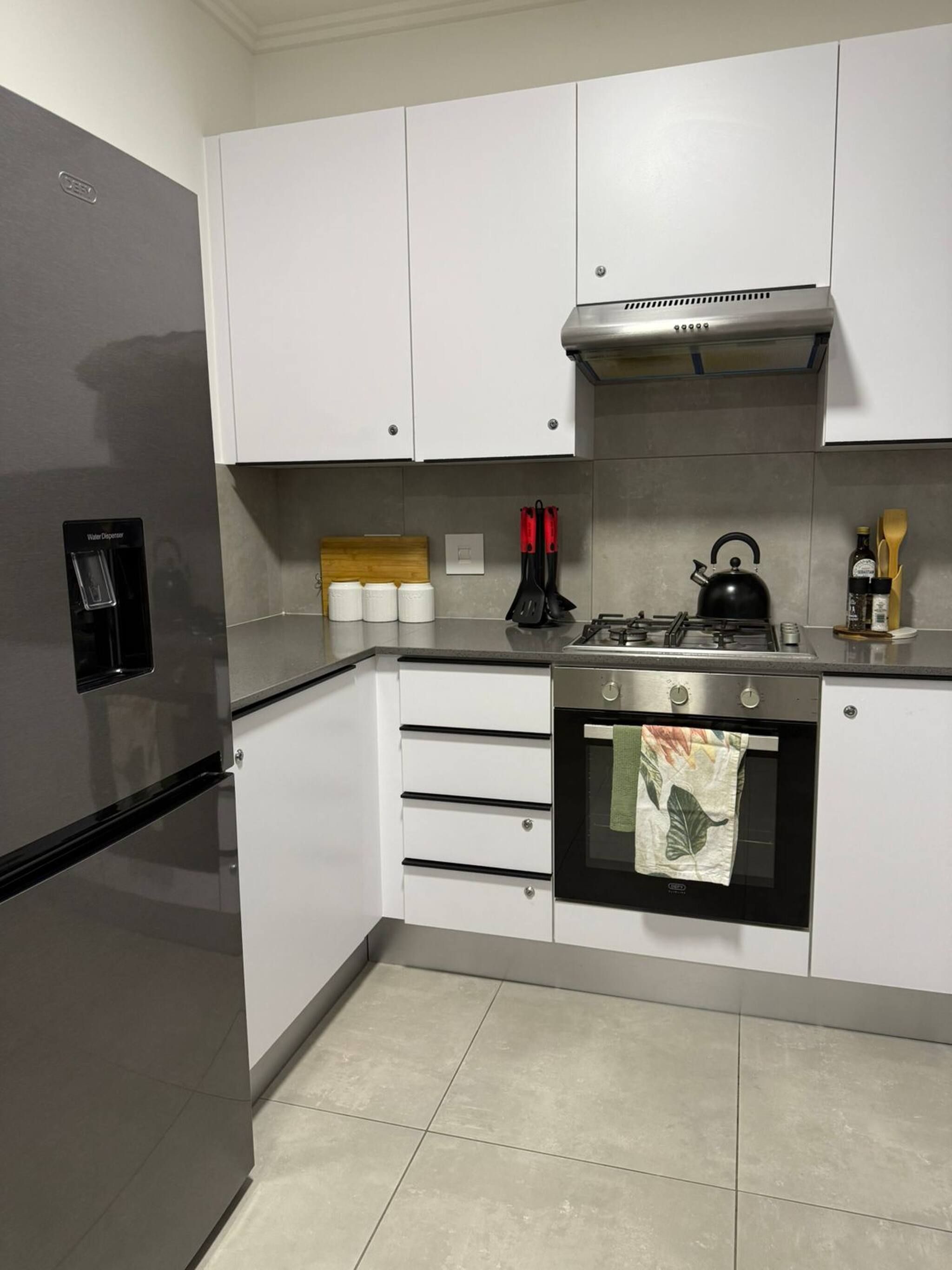 Una cocina moderna con un refrigerador de acero inoxidable, horno empotrado y cocina a gas.