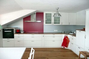 Una cocina moderna con armarios blancos, una pared de acento roja y suelo de madera.