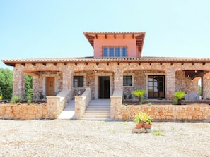 A stone house with a tiled roof, a central staircase, and potted plants. - Cabin in Muro With Swimming Pool (Muro)