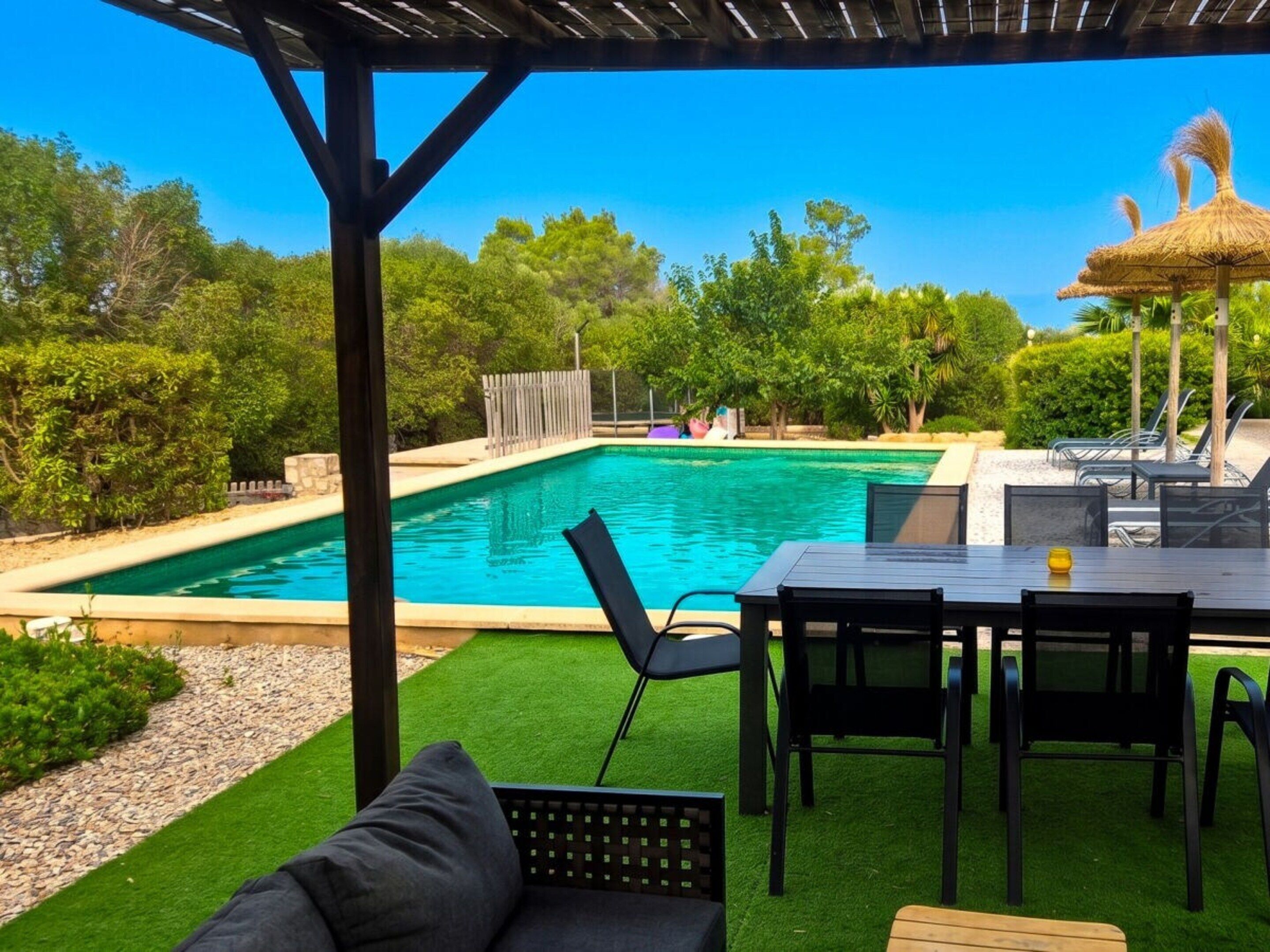 A pool area with a covered seating area and a table.