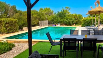 A pool area with a covered seating area and a table.
