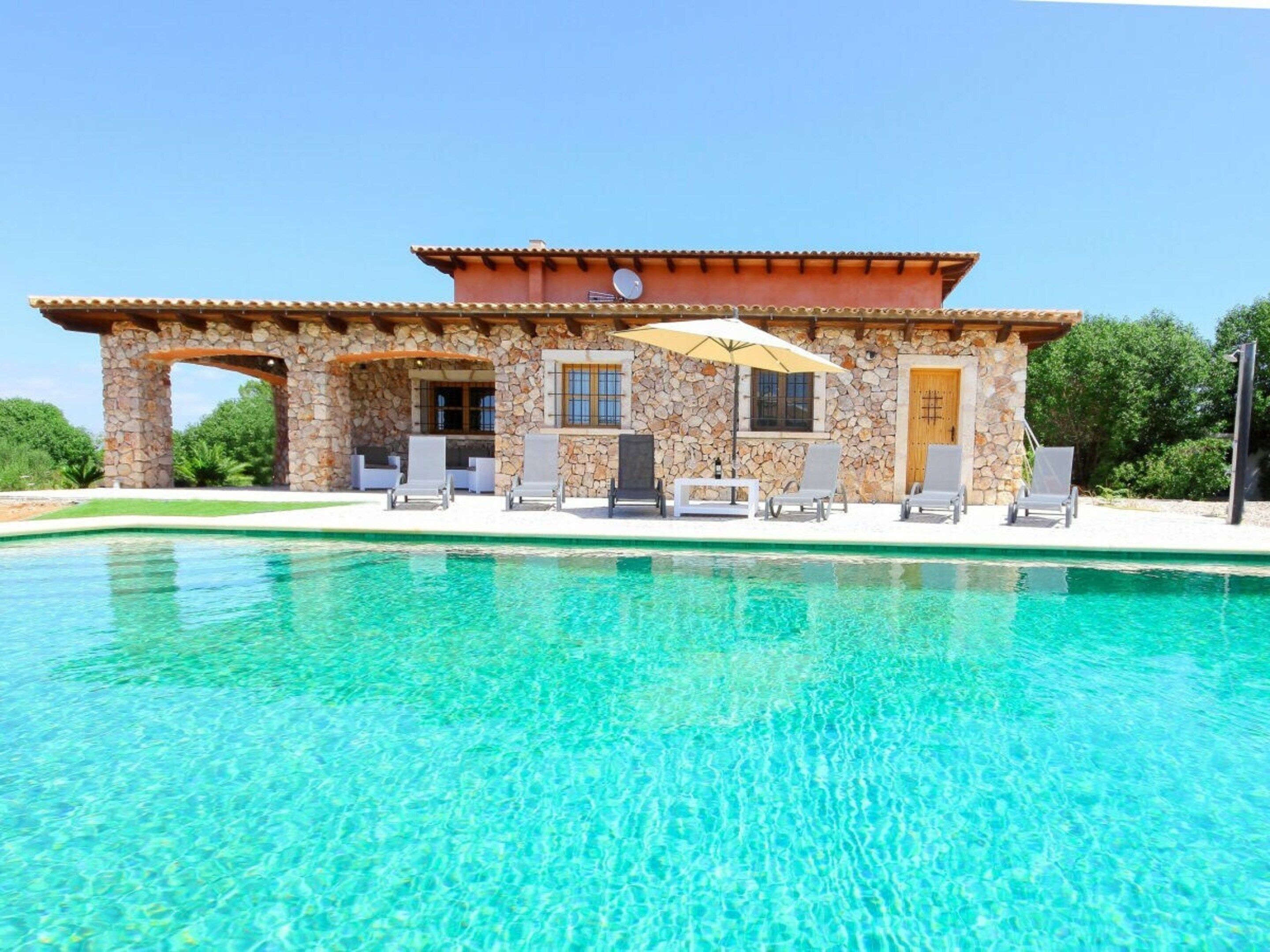 A stone building with a pool in front.