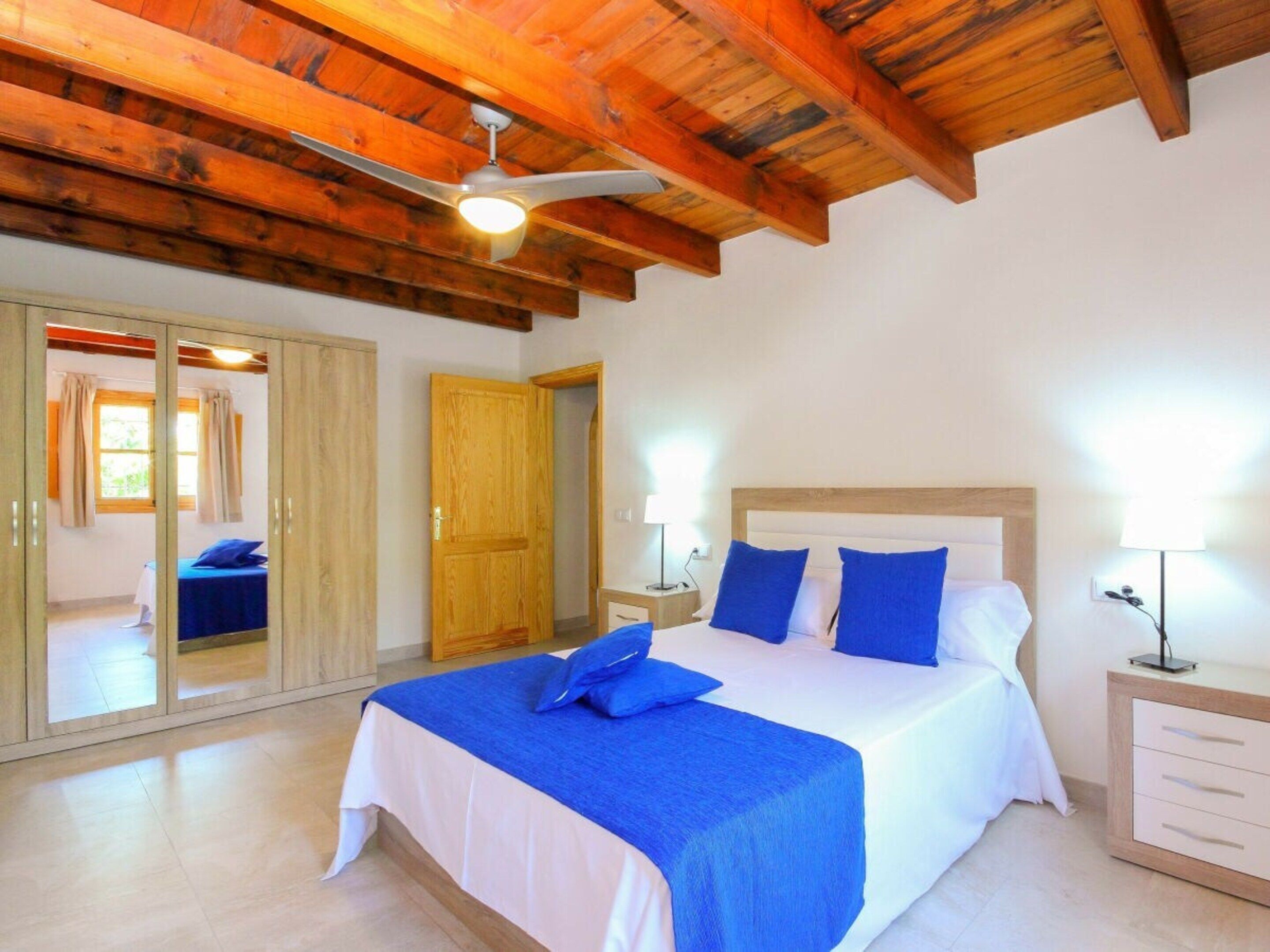 A bedroom with a bed, bedside tables, a wardrobe, and a ceiling fan.