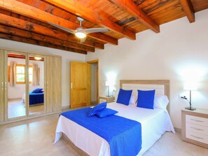 A bedroom with a bed, bedside tables, a wardrobe, and a ceiling fan. - Cabin in Muro With Swimming Pool (Muro)