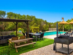 Terrassa exterior amb piscina, mobles de fusta i una barbacoa.