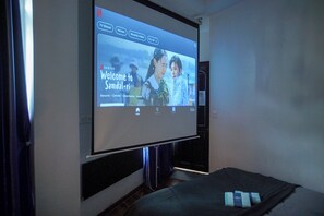 Eine projizierte Leinwand zeigt den Film 'Welcome to Samdal-ri' mit Auswahlmöglichkeiten für Fernsehsendungen, Filme und neu hinzugefügte Inhalte.