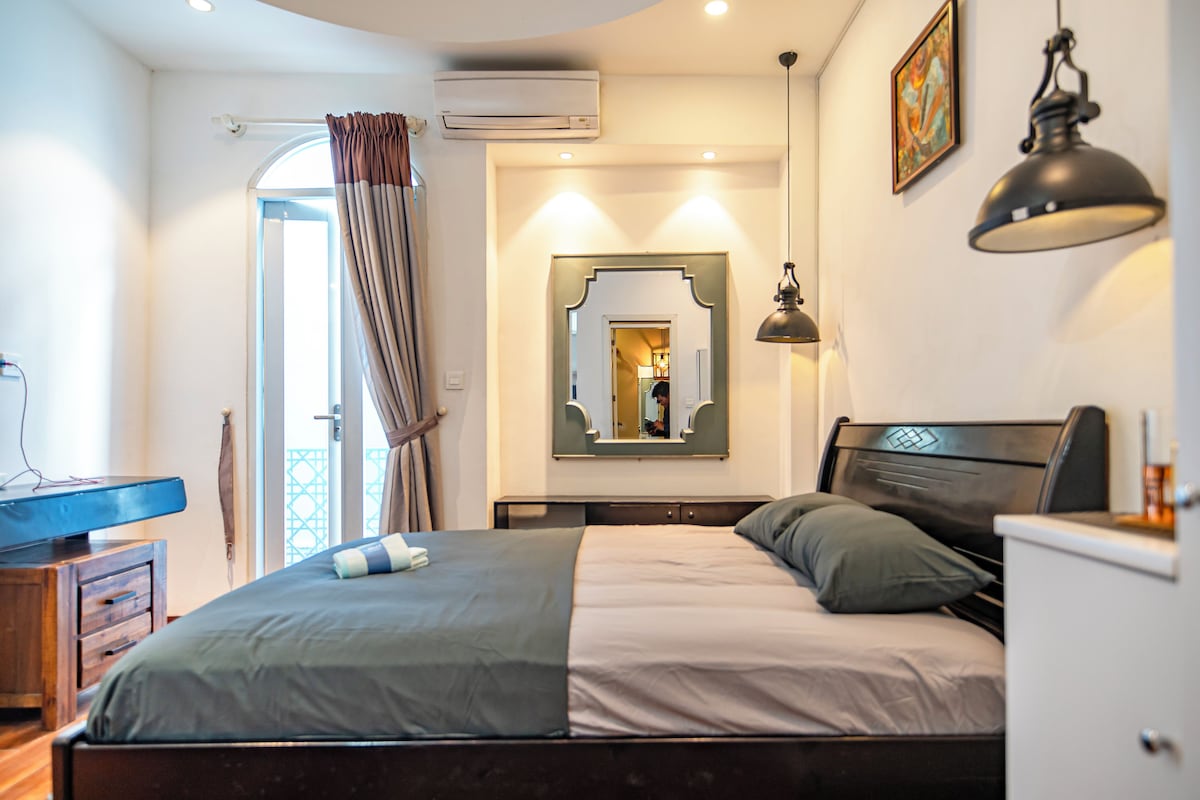 Ein Schlafzimmer mit Bett, Schreibtisch, Stuhl, Kleiderschrank und Spiegel.