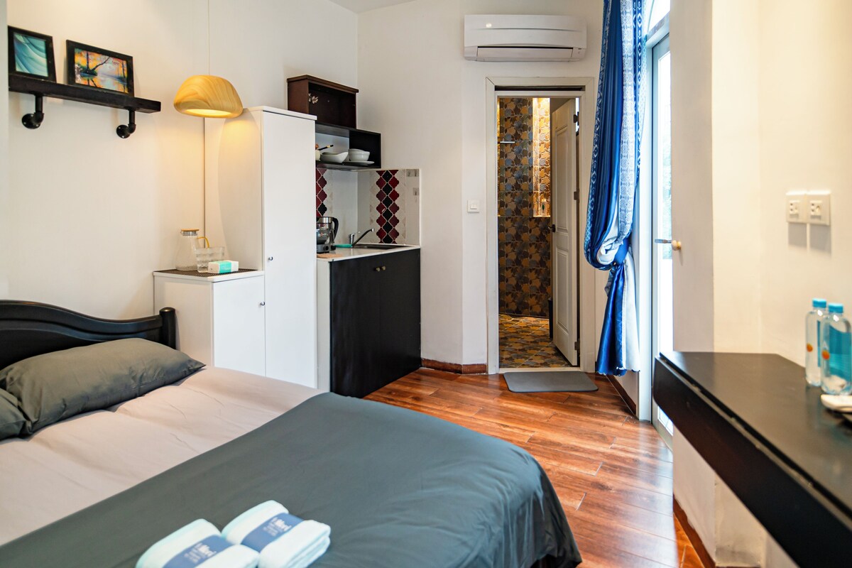 Ein Schlafzimmer mit Bett, Nachttisch, Lampe, Kleiderschrank und einer offenen Tür zu einem Badezimmer.