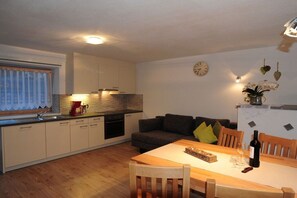 Un espace de vie compact comprenant un coin cuisine, un espace repas et un coin salon confortable.