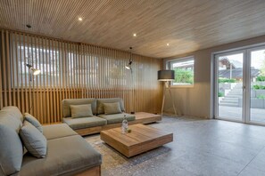 A modern living room with a sectional sofa, a wooden coffee table, and a large window with a view of the outdoors. - Holiday apartment with 1 bedroom (Oberstdorf)