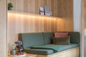 A wooden wall with a shelf holding decorative items and a green sofa with cushions. - Holiday apartment with 1 bedroom (Oberstdorf)
