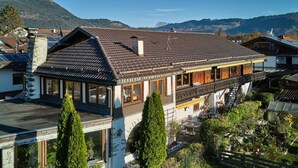 A traditional chalet with a sloped roof, wooden balcony, and a view of the surrounding mountains. - THE COUNTRY VILLA || Garmisch-Partenkirchen (Garmisch-Partenkirchen)