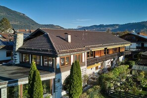 Een chalet in traditionele stijl met een schuin dak, een houten balkon en uitzicht op de omliggende bergen.