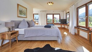 A bedroom with a bed, a television, a window with curtains, and a painting on the wall. - THE COUNTRY VILLA || Garmisch-Partenkirchen (Garmisch-Partenkirchen)