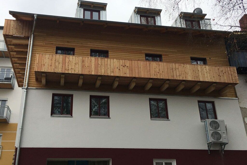 En bygning med flere etager, en træbalkon og en aircondition.