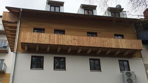 A multi-story building with a wooden balcony and an air conditioning unit. - Holiday home with 3 bedrooms (Viechtach)