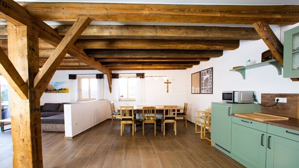 A rustic kitchen with wooden beams, a dining table with chairs, and a green cabinet. - Holiday home with 3 bedrooms (Viechtach)
