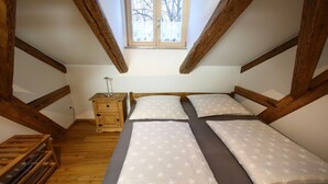A small, attic-style bedroom with a wooden ceiling and a window. There is a bed with white bedding and a nightstand with a lamp. - Holiday home with 3 bedrooms (Viechtach)