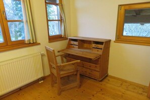 A room with a wooden desk, chair, and radiator. There are windows with curtains. - Holiday home in Chieming with swimming pool (Chieming)
