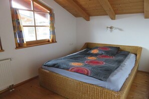 A room with a single bed, a window with curtains, a radiator, and a wooden ceiling. - Holiday home in Chieming with swimming pool (Chieming)