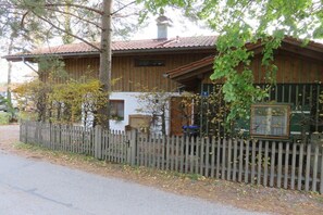 A wooden house with a fenced yard, a chimney, and a small porch. - Holiday home in Chieming with swimming pool (Chieming)