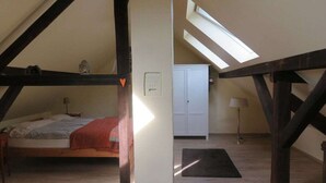 Een slaapkamer met een schuine kap, een bed, een kledingkast en een dakraam.
