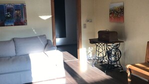 Een woonkamer met een bank, een bijzettafeltje met een doos, en een schilderij aan de muur.
