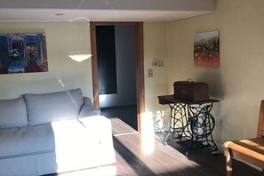 En stue med en sofa, et lille bord med en æske, og et billede på væggen.