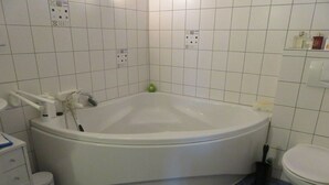 Een badkamer met een groot bad, een toilet en een wastafel.