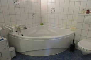 Et badeværelse med et stort badekar, et toilet og en håndvask.