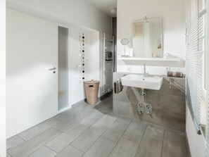 A modern bathroom with a white sink, mirror, and towel rack. - Holiday Apartment With 2 Bedrooms (Norderney)
