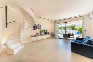 A modern living room with a spiral staircase, a flat-screen TV, and a sofa. - Solemar Sicilia - Villa Mondello (Palermo)