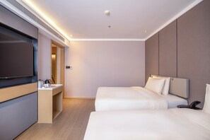 A hotel room with a flat-screen TV, a bedside table with a kettle, a phone, and a bed with white bedding. - DALIAN xinghaiguangchang xianlu yaduo (Dalian)