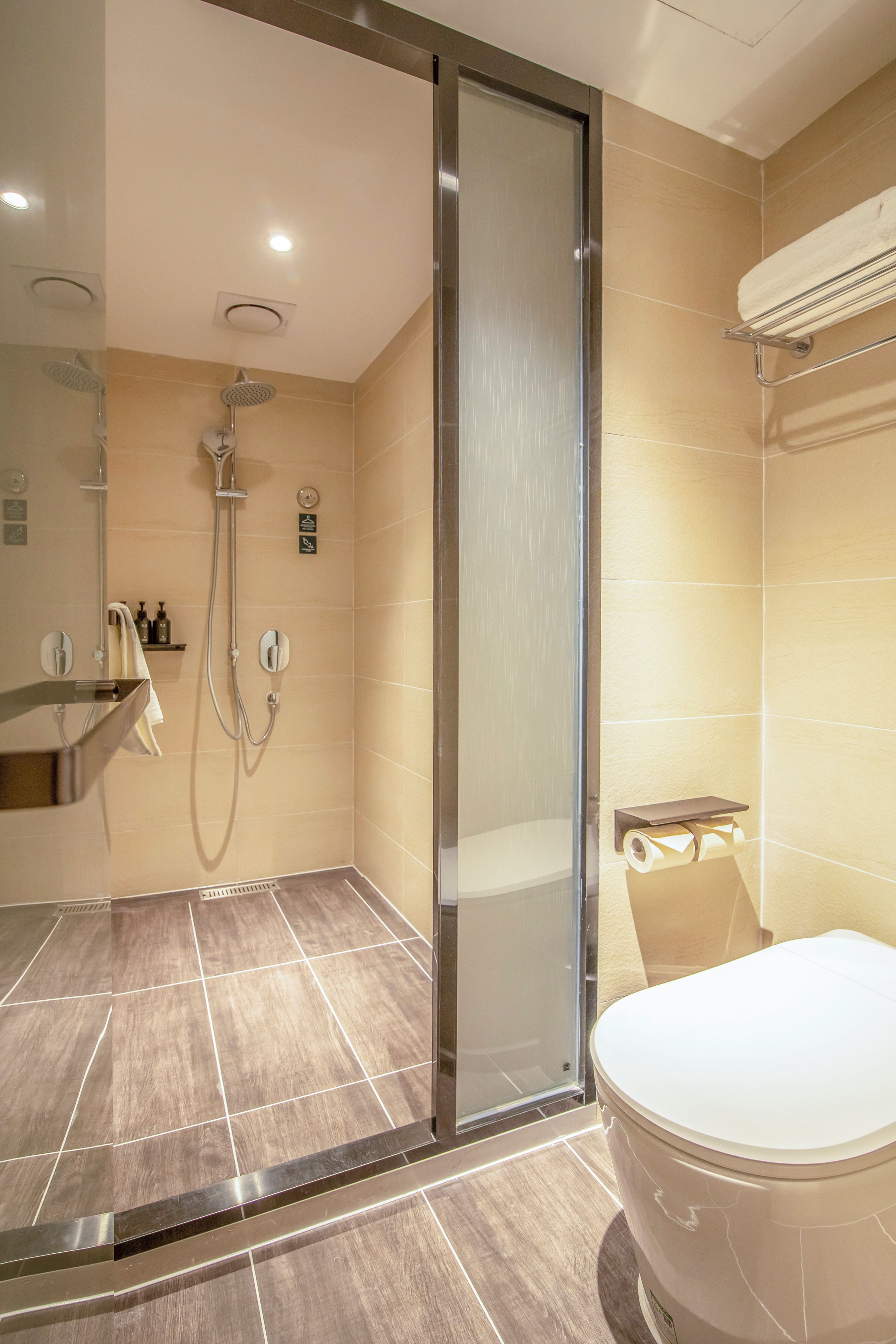A modern bathroom with a glass-enclosed shower, a toilet, and a sink.