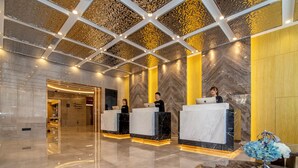 A modern reception area with marble counters, a geometric ceiling design, and a polished floor. - DALIAN xinghaiguangchang xianlu yaduo (Dalian City)