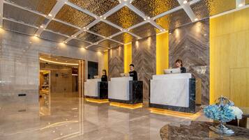 A modern reception area with marble counters, a geometric ceiling design, and a polished floor.